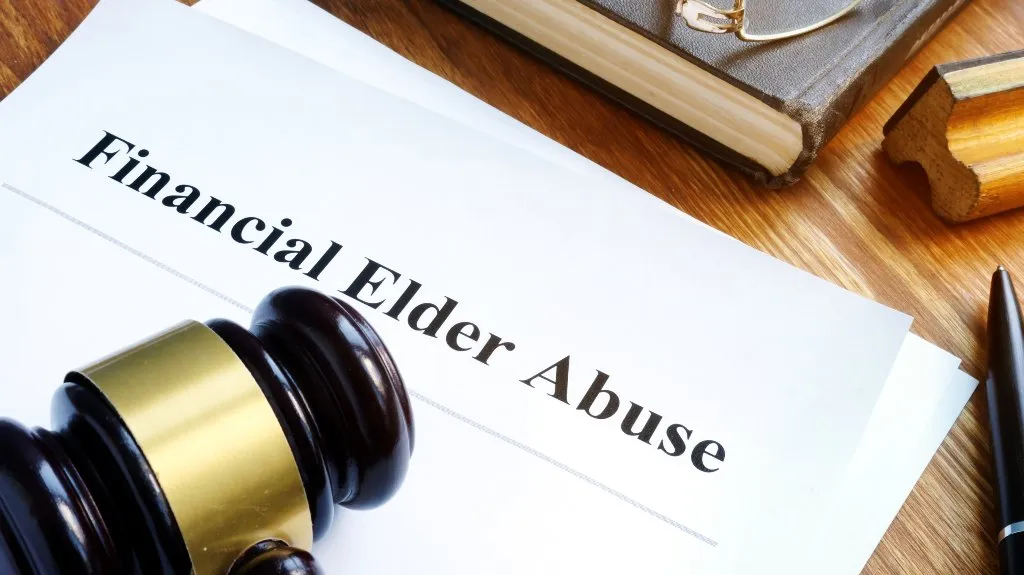 Document titled "Financial Elder Abuse" on wooden desk with judge's gavel, book, and pen.