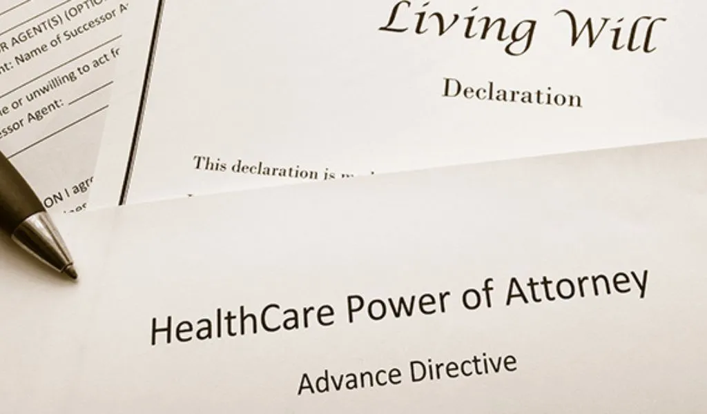 Close-up of legal documents titled "Living Will Declaration" and "HealthCare Power of Attorney Advance Directive" with a pen.